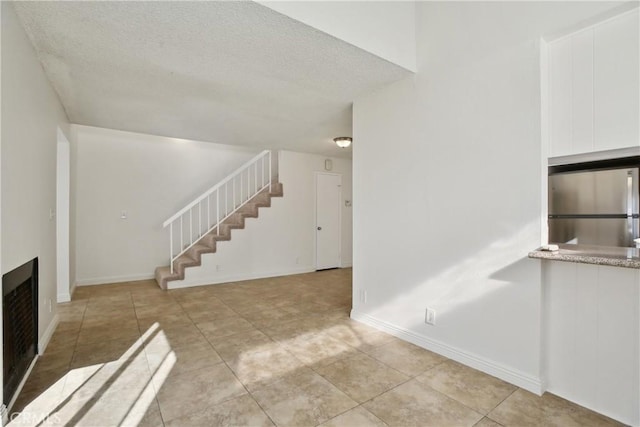 unfurnished living room with a textured ceiling and light tile patterned floors