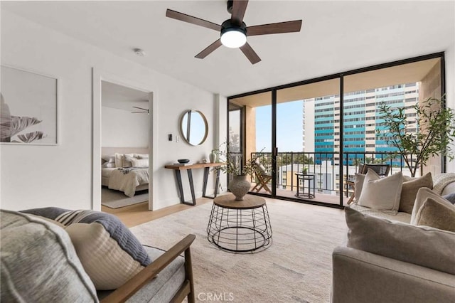 living room featuring ceiling fan and a wall of windows