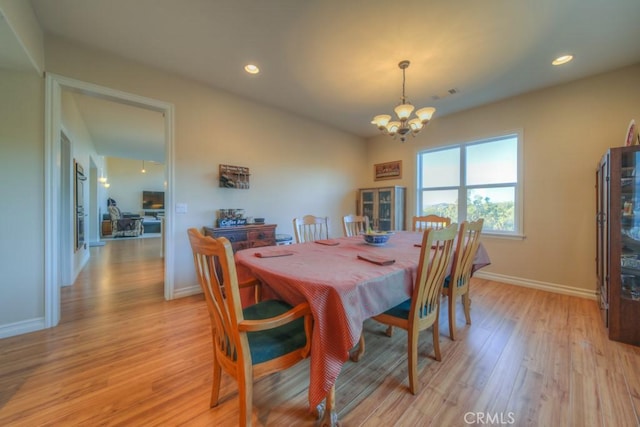 dining area with light hardwood / wood-style flooring and a chandelier