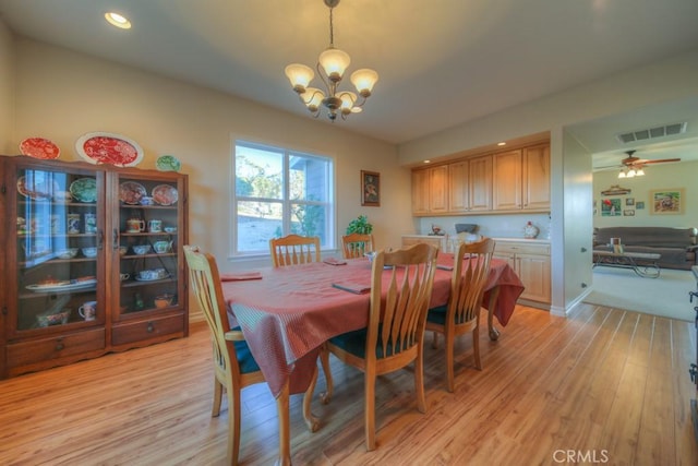 dining room with ceiling fan with notable chandelier and light hardwood / wood-style flooring