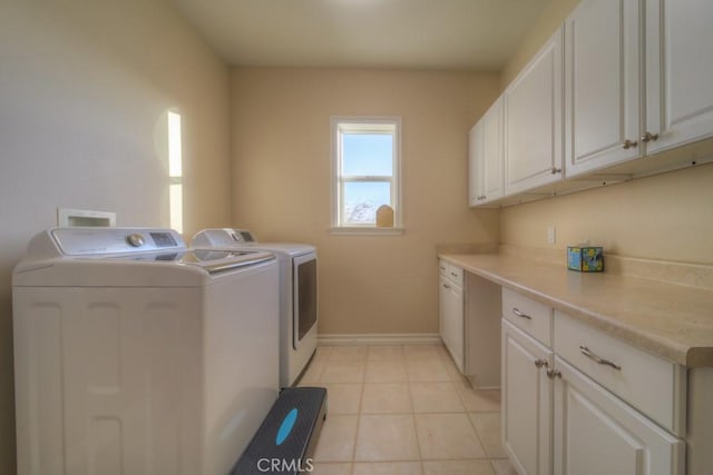 laundry room with washer and dryer, cabinets, and light tile patterned flooring