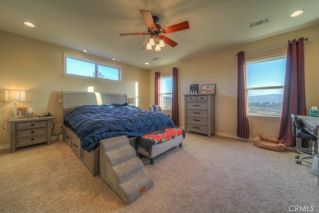 bedroom featuring ceiling fan, light colored carpet, and multiple windows