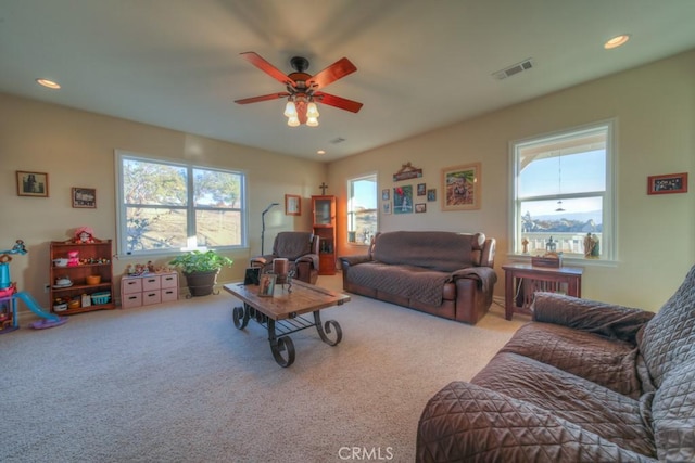 living room with light carpet, ceiling fan, and plenty of natural light