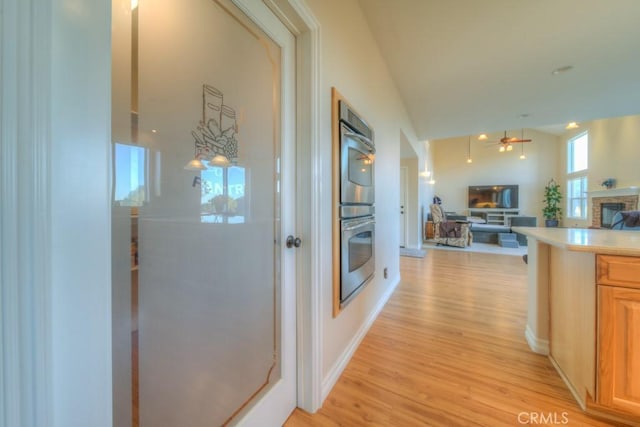 corridor with lofted ceiling and light hardwood / wood-style floors