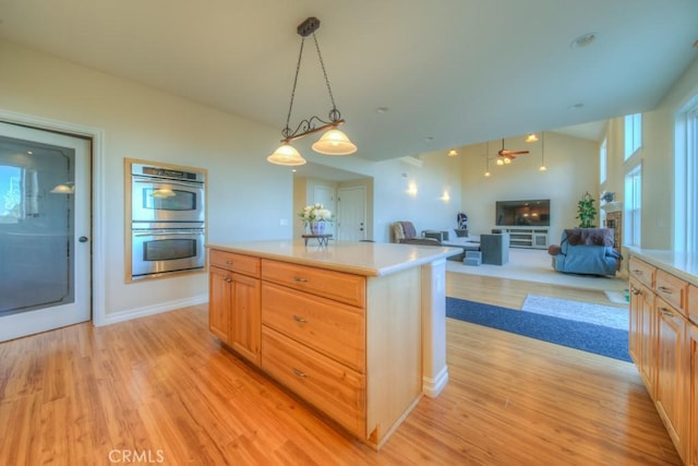 kitchen featuring decorative light fixtures, a center island, light hardwood / wood-style floors, light brown cabinetry, and double oven