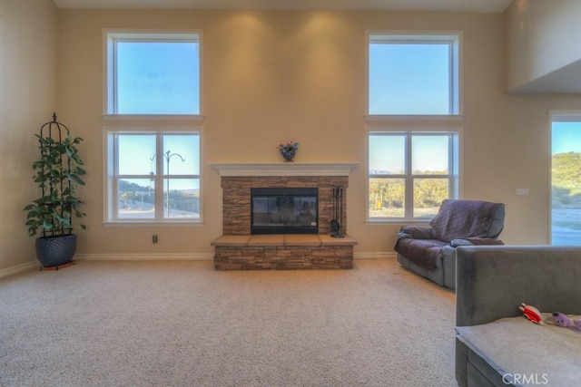 living room featuring carpet floors, a wealth of natural light, and a stone fireplace