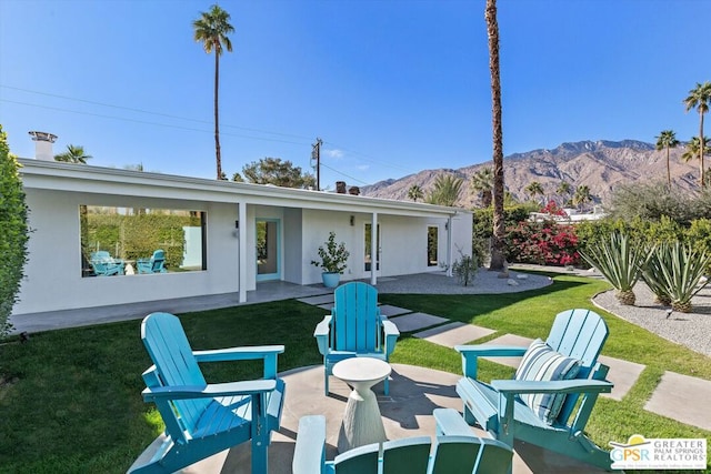 back of property featuring a mountain view, a lawn, and a patio