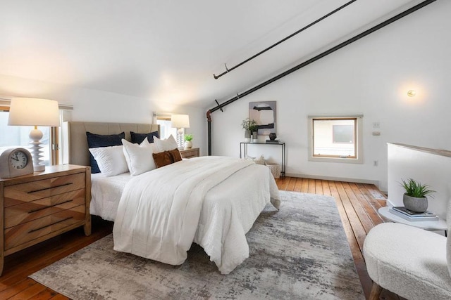 bedroom featuring lofted ceiling, wood-type flooring, and multiple windows