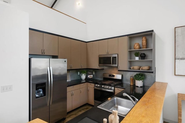 kitchen featuring butcher block countertops, kitchen peninsula, decorative backsplash, sink, and stainless steel appliances