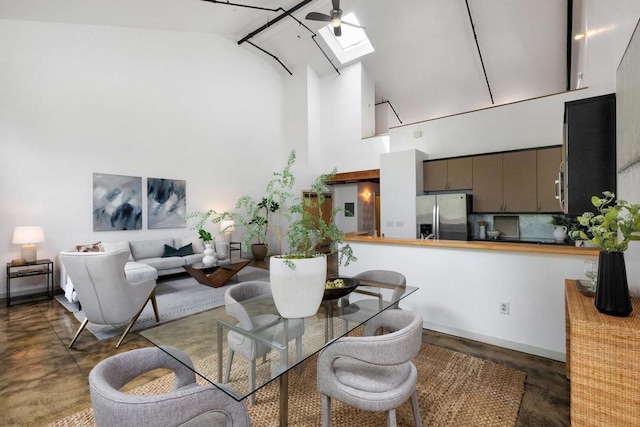 dining area with ceiling fan, high vaulted ceiling, and a skylight