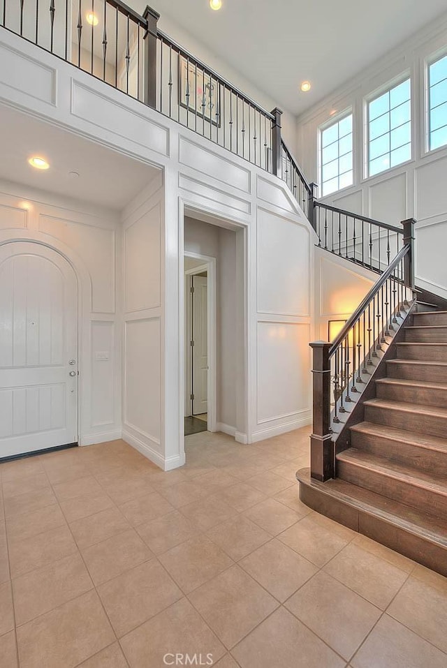 foyer with light tile patterned flooring and a towering ceiling