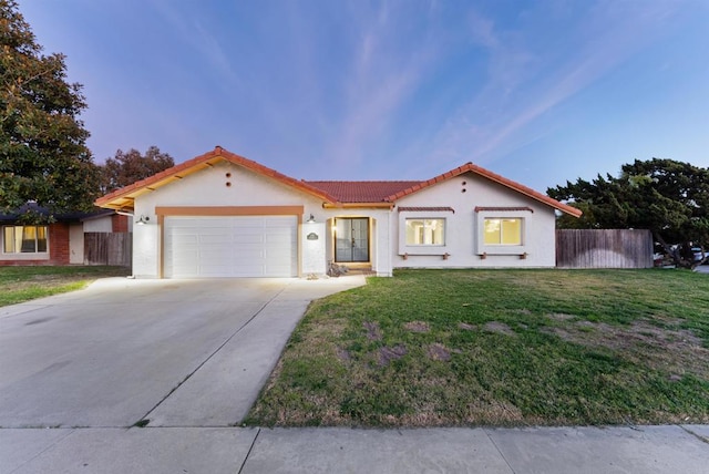 mediterranean / spanish-style house with a garage and a yard