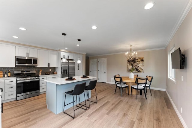 kitchen with pendant lighting, a kitchen island, white cabinetry, stainless steel appliances, and a chandelier