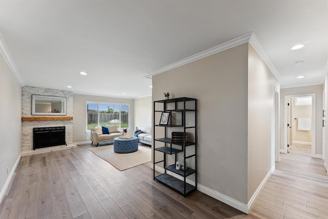 living room featuring ornamental molding, light hardwood / wood-style floors, and a stone fireplace