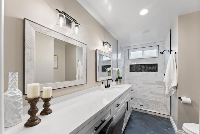 bathroom featuring tile patterned floors, toilet, vanity, and a tile shower