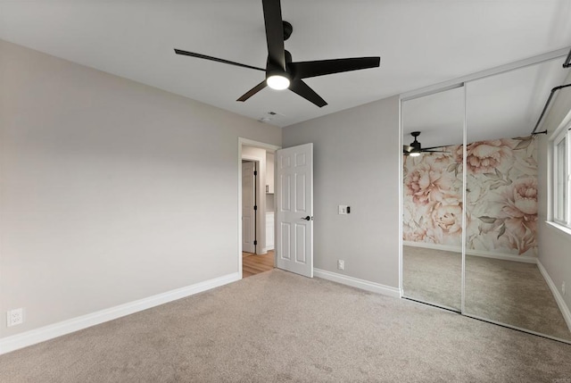 unfurnished bedroom featuring ceiling fan, a closet, and light carpet