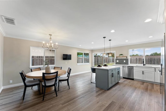 kitchen featuring stainless steel dishwasher, hanging light fixtures, gray cabinetry, and a center island