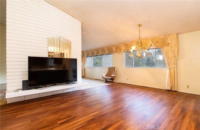 unfurnished living room with wood-type flooring, an inviting chandelier, vaulted ceiling, and a wealth of natural light