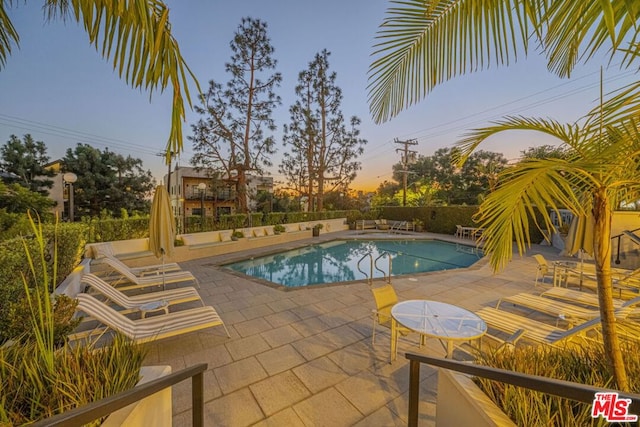 pool at dusk featuring a patio area