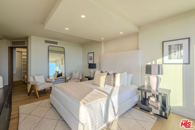 bedroom featuring a spacious closet and light hardwood / wood-style floors