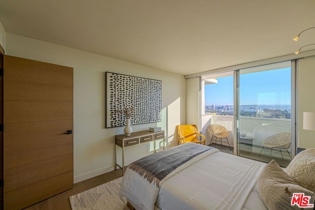 bedroom with a wall of windows and wood-type flooring