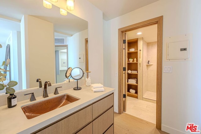 bathroom featuring hardwood / wood-style floors, electric panel, and vanity