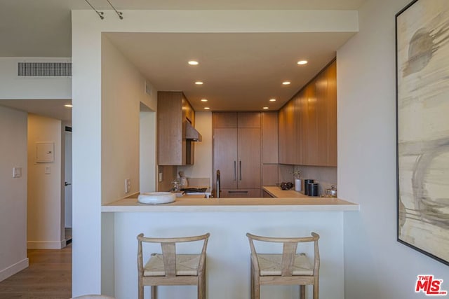 kitchen with a breakfast bar, dark hardwood / wood-style floors, and kitchen peninsula