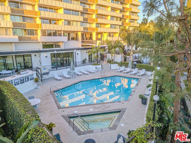 view of swimming pool with a hot tub and a patio area