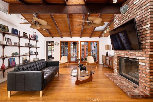 living room featuring wood ceiling, light hardwood / wood-style flooring, ceiling fan, a brick fireplace, and french doors