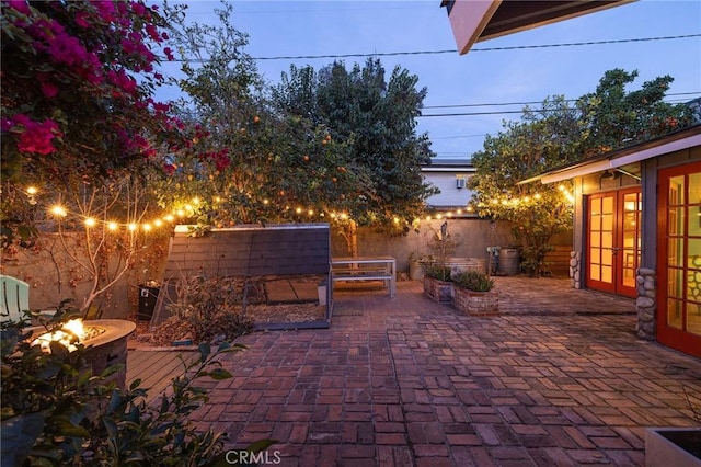 patio terrace at dusk featuring french doors and an outdoor fire pit