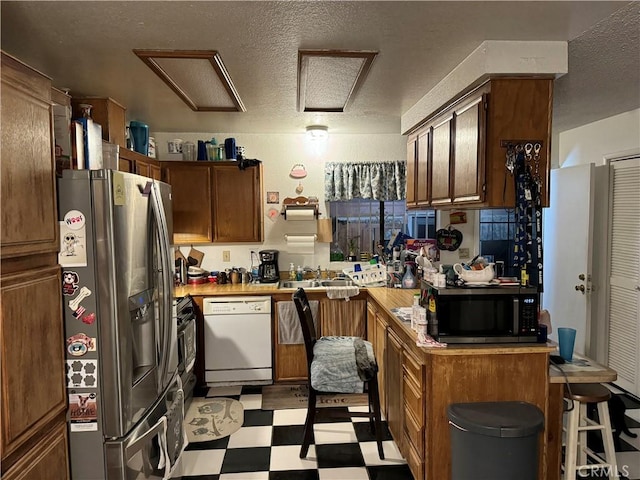 kitchen with kitchen peninsula, sink, white dishwasher, a textured ceiling, and stainless steel fridge