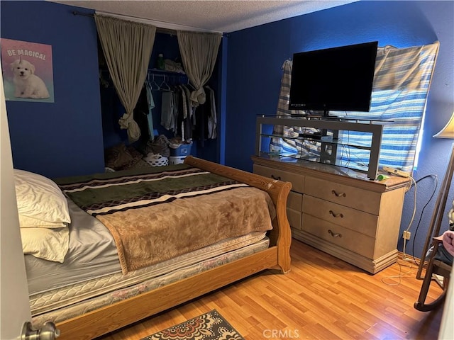 bedroom with a textured ceiling, a closet, and wood-type flooring