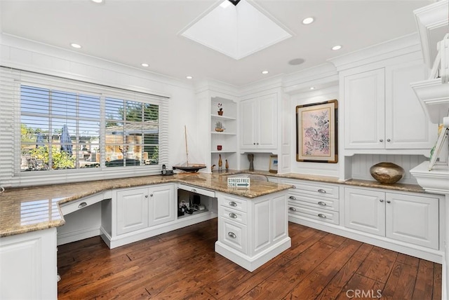 unfurnished office featuring built in desk, a skylight, dark hardwood / wood-style floors, and crown molding