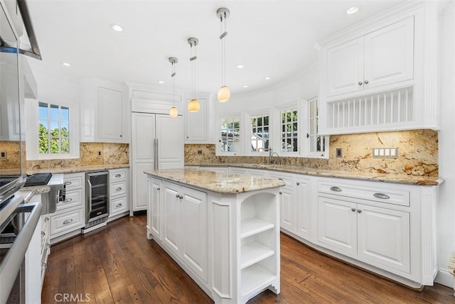 kitchen with pendant lighting, a center island, dark wood-type flooring, white cabinets, and beverage cooler