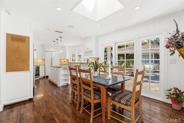 dining room featuring dark wood-type flooring, crown molding, and a skylight