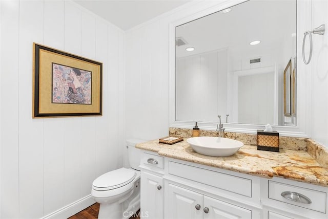 bathroom featuring toilet, vanity, crown molding, and hardwood / wood-style flooring