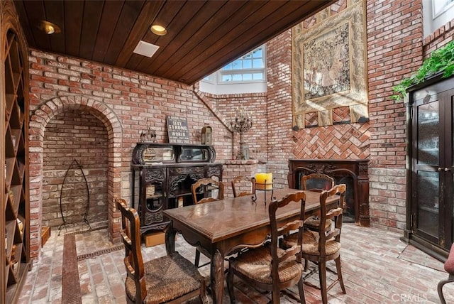 interior space featuring wooden ceiling, brick wall, and a tile fireplace