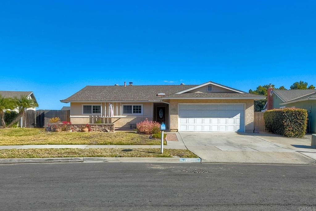 ranch-style home featuring a garage and a front lawn