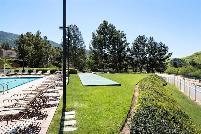 surrounding community featuring a mountain view, a pool, and a lawn