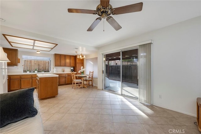 kitchen with light tile patterned flooring, ceiling fan with notable chandelier, and a center island