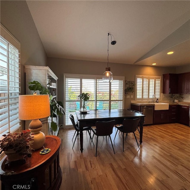 dining room with light hardwood / wood-style floors, sink, and vaulted ceiling