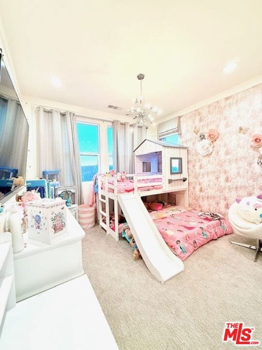 carpeted bedroom featuring ceiling fan with notable chandelier