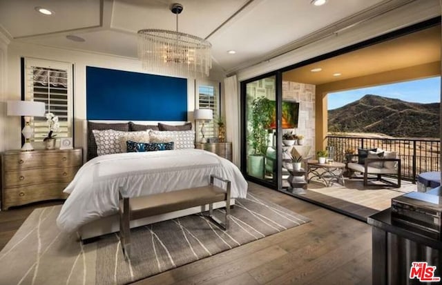 bedroom with a mountain view, vaulted ceiling, hardwood / wood-style flooring, and an inviting chandelier