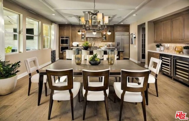 dining room featuring beverage cooler, an inviting chandelier, and light hardwood / wood-style floors