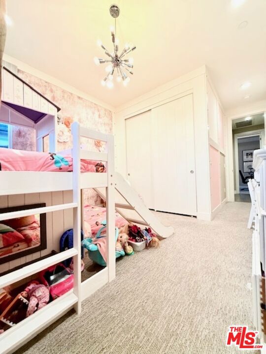 carpeted bedroom with a closet, a chandelier, and crown molding