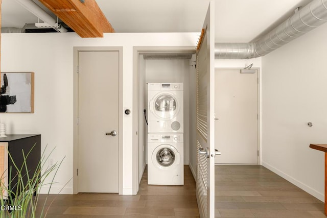 laundry room featuring dark hardwood / wood-style floors and stacked washer and clothes dryer