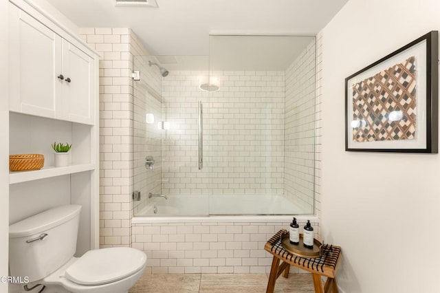 bathroom featuring toilet and combined bath / shower with glass door