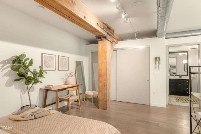 bedroom with a closet, rail lighting, and wood-type flooring