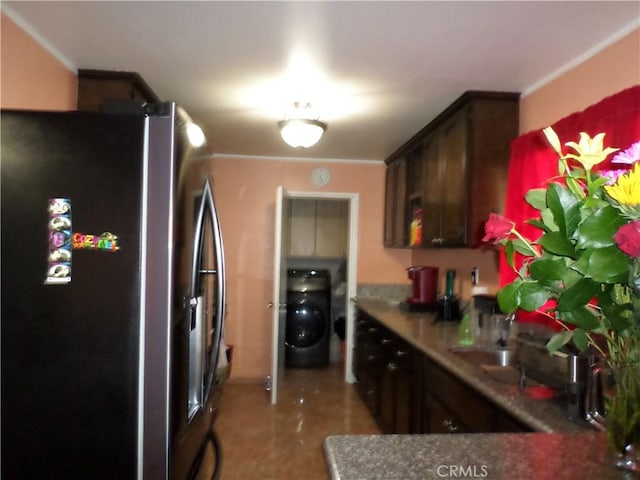 kitchen featuring stainless steel refrigerator with ice dispenser, sink, dark brown cabinetry, and washer / dryer