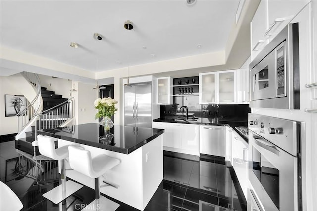 kitchen with granite finish floor, a sink, dark countertops, and built in appliances